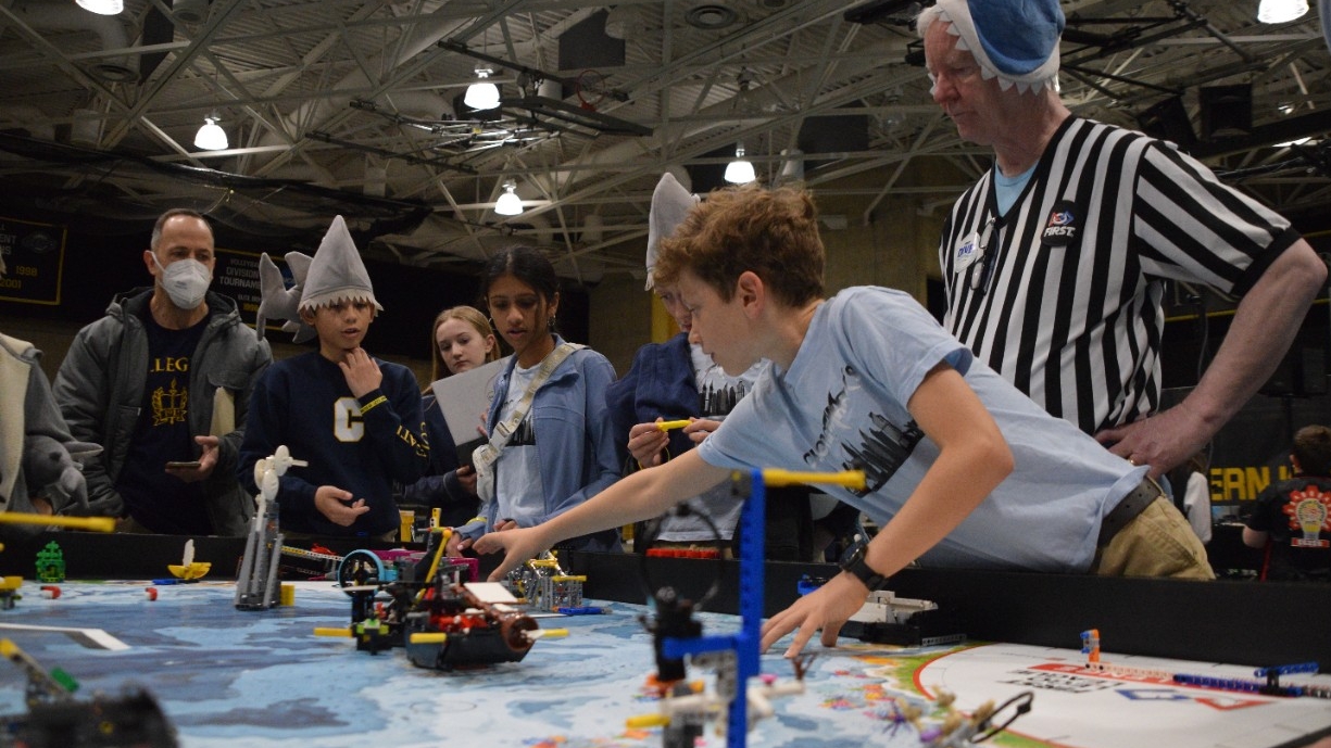 KY FLL Challenge Elementary aged students wearing fun shark hats intently watch their team's LEGO robot perform at the annual Kentucky robotics competition at Northern Kentucky University.