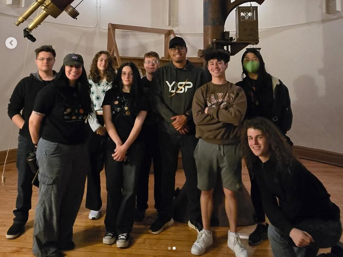 Physics and Astronomy Club members take a group photo in front of a very large telescope