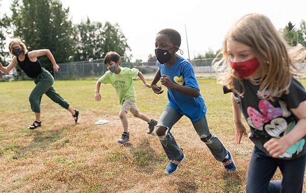 4 kids running outside with face masks on