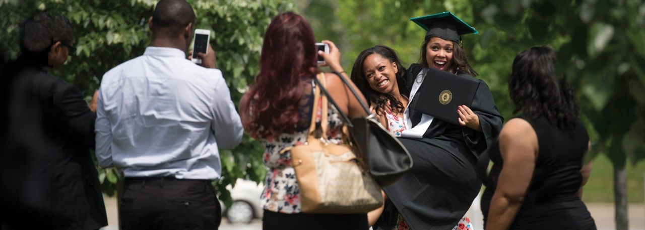 Graduating student posing for photographs outside.