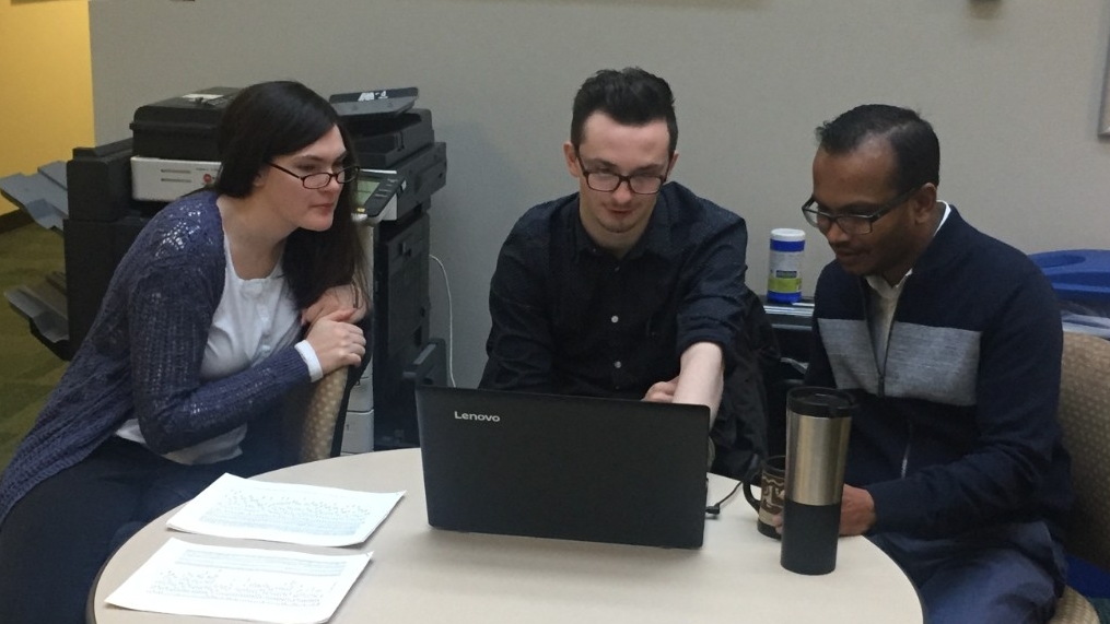 Three people sharing a laptop screen